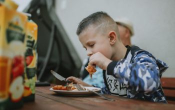 Young boy savoring a grilled chicken meal during an outdoor barbecue.
